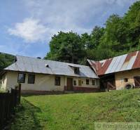 A family house in Hačava with a metal roof surrounded by nature and greenery.