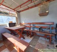 Wooden interior with a bench, table, window, and birdcage in a cabin.
