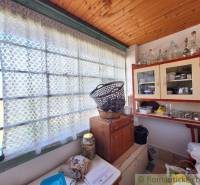 The interior of a cottage with a wooden ceiling, cabinets, and a basket on the window with a curtain.