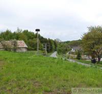 A rural landscape in Kečkovce with green gardens, houses, and a country road.