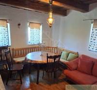 Rustic interior of a cottage with wooden furniture, a bench, and chandeliers.