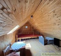 An attic with wooden walls and simple furniture in a cottage.