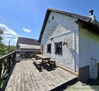 Cottage in Podkriváni with a wooden terrace and a bench under the blue sky.