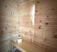 Sauna in a wooden interior of a cabin with a ladle and bucket on the bench.