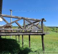 A wooden terrace at the cottage in Podkriváň with a view of the green meadow.