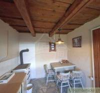 Interior of the Cottage: wooden ceiling, table with chairs, stove. Rustic atmosphere.