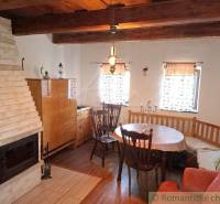 Wooden beams in the cabin with a fireplace and dining table create a cozy atmosphere.