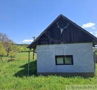 A cottage in Podkriváni with a simple facade in a natural setting under a blue sky.