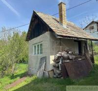 A family house in Kokava nad Rimavicou with a wooden roof and a pile of wood by the gate.