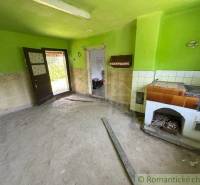 A dusty room in a family house with an old stove and green walls.