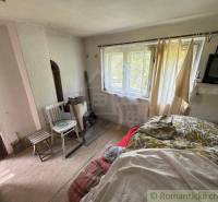 Interior of a family house with a bed, chair, table, and a small television.