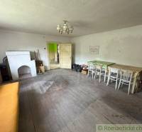 Room in a family house with wooden flooring, a sofa, and a stove.