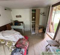 A room in a family house with a bed, a table, a wardrobe, and books on the table.