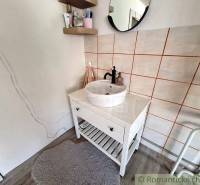 A small bathroom in a family house with a sink, mirror, and shelves.