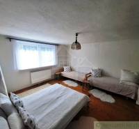 A bedroom in a family house with three beds and a wooden floor.