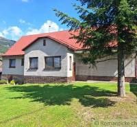 A family house in Telgárt with a red roof and a grassy garden, with a landscape in the background.