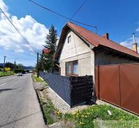 A family house in Telgárt with a wooden fence, blue sky, and a road.