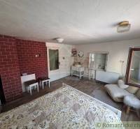 A room with white furniture, an exposed brick wall, and a comfortable bed in a family house.