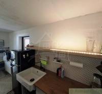 A kitchen in a family house with a wooden countertop and a black refrigerator.
