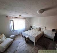 A bedroom in a family house with white furniture, a comfortable sofa, and wooden flooring.