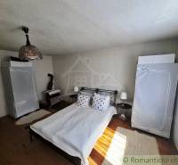 A bedroom in a family house with a metal bed and a wood stove.