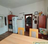 Dining room with a wooden table, kitchen unit, decorations, and accessories in a family house.