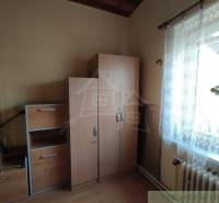 A room in a family house with simple furniture, white curtain, light from the window.