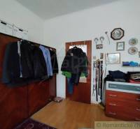 In the room of the family house, there is a wardrobe with jackets, a dresser, and decorations on the wall.