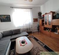 Living room in a family house with a corner sofa, wooden wall unit, and hall decoration.