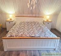 A wooden, white interior with a stylish bed and nightstands. The family house offers a pleasant atmosphere.