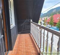 A balcony of a family house with a view of nature, roofs, and trees.