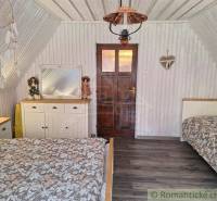 Bedroom with sloped walls, dreamcatcher, white furniture, and rustic wooden floors in a family house.