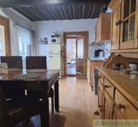 The dining room is adorned with solid wooden furniture as part of the family home, complemented by wicker and rustic details.