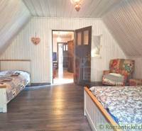 Attic room with white paneling, wooden beds, a comfortable armchair, ideal for a family house.