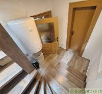 Stairs leading to the attic, a hallway with doors and a water heater in a family house.