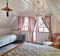Attic room with a slanted ceiling, two beds, an armchair, and a dreamcatcher.