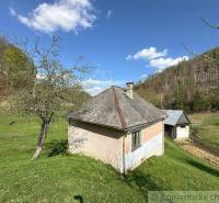 A cottage amidst greenery with mountains in the background. Rural landscape and family house.