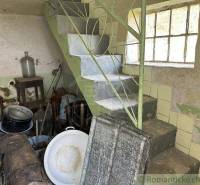 An old cellar with a staircase, a window, and a lot of unnecessary items evokes the image of a family house.