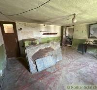 An old cottage interior with a table next to a mirror and a door to another room.