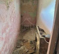 Abandoned narrow room with peeling plaster and broken floor in a family house.