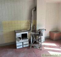 Traditional family house with a vintage stove, old table, and a wooden storage cabinet.