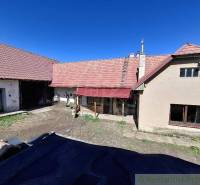 An older family house with a yard, a red roof, and a garage in the countryside.