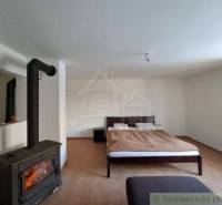 Interior of a family house with a fireplace and a double bed on a wooden floor.