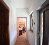 A hallway in a family house with wooden and white walls, leading to a room with a bunk bed.