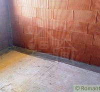 A construction site with a brick wall and a window, part of a family house under construction.
