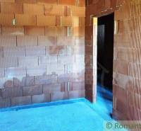 A family house under construction with unplastered brick walls and an open door space.
