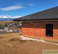 A family house under construction with a view of snow-covered mountains and hills.