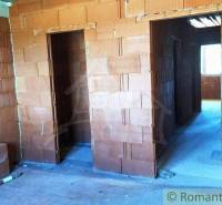 The shell construction of a family house, rooms with unplastered bricks, windows letting in light.