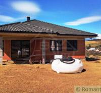 A family house under construction in the countryside, with a sloped roof and open space.