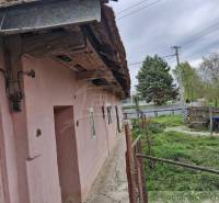 An older family house with a yard, garden, and fencing in the countryside.